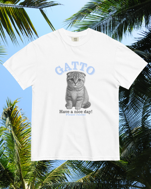 White t-shirt with a cat graphic and 'GATTO Have a nice day!' text against a tropical background
