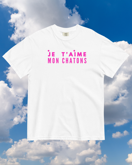 White t-shirt with pink text against a blue sky background