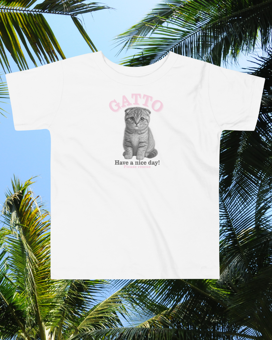 White t-shirt with a cat graphic and text 'Gatto Have a nice day!' against a palm tree background