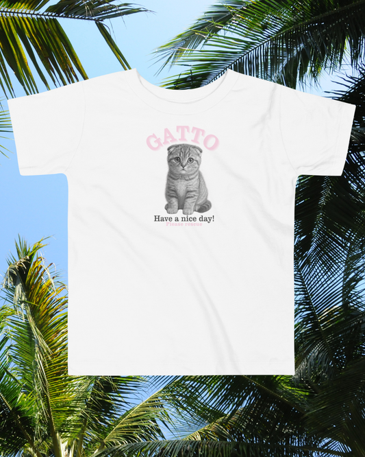 White t-shirt with a cat graphic and text 'Gatto Have a nice day!' against a palm tree background