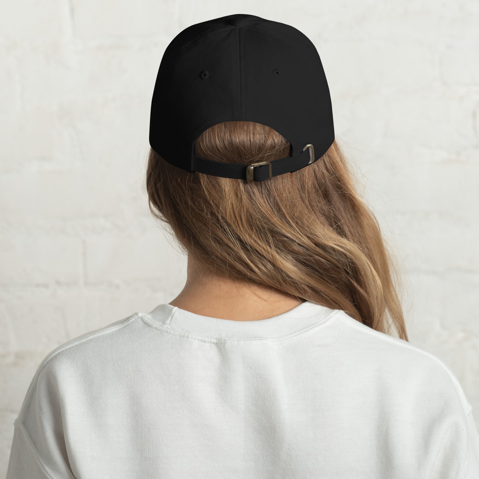 Person wearing a black cap from behind on a light gray background