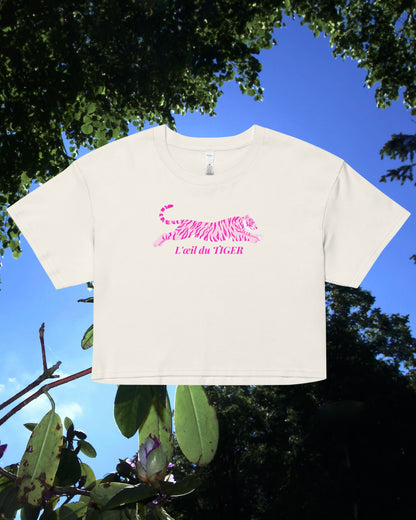 White crop top with pink text against a blue sky and green foliage background