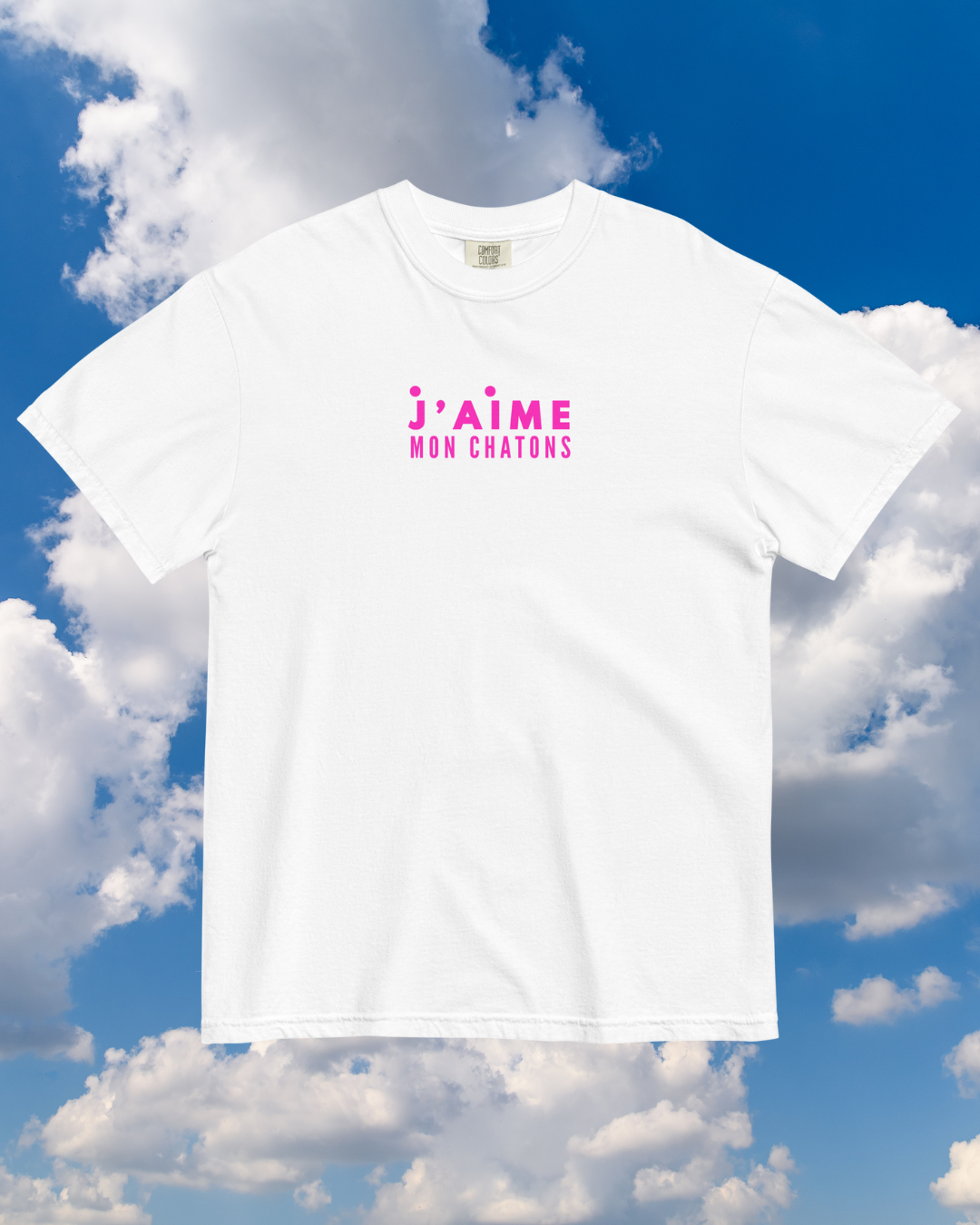 White t-shirt with pink text against a blue sky background