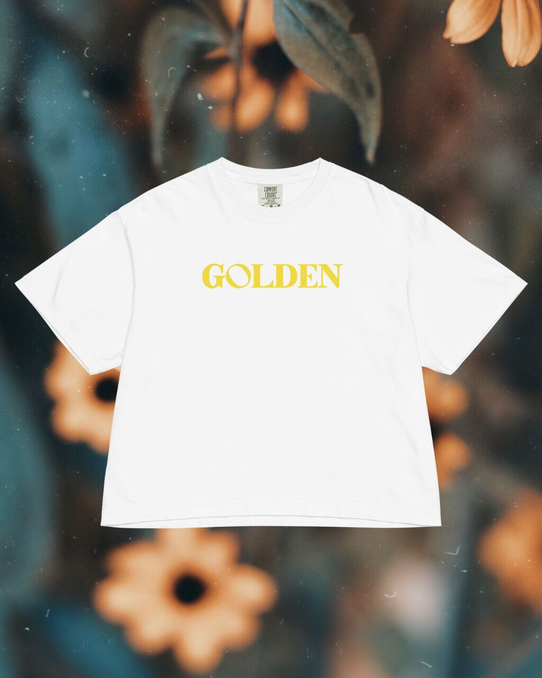 White t-shirt with 'GOLDEN' text on a floral background