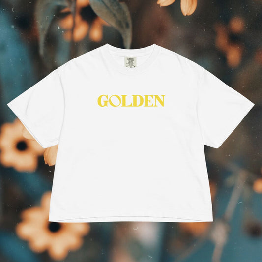 White t-shirt with 'GOLDEN' text on a blurred floral background