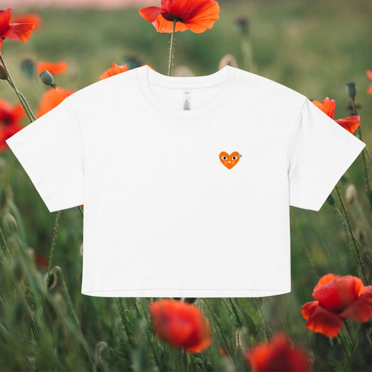 White t-shirt with a small orange heart design in a field of red poppies