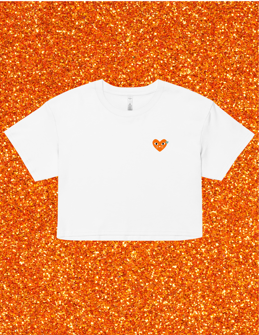 White t-shirt with a small orange logo on an orange glittery background