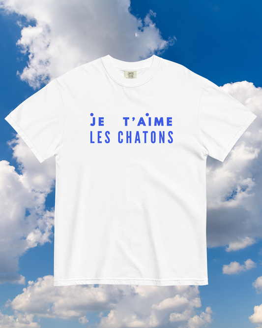 White t-shirt with blue text 'JE T'AIME LES CHATONS' against a blue sky with clouds