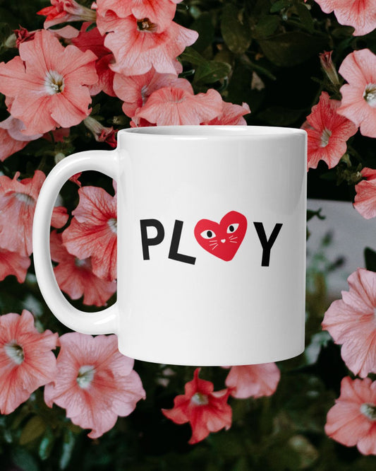 White mug with 'PLAY' and a heart design on a floral background