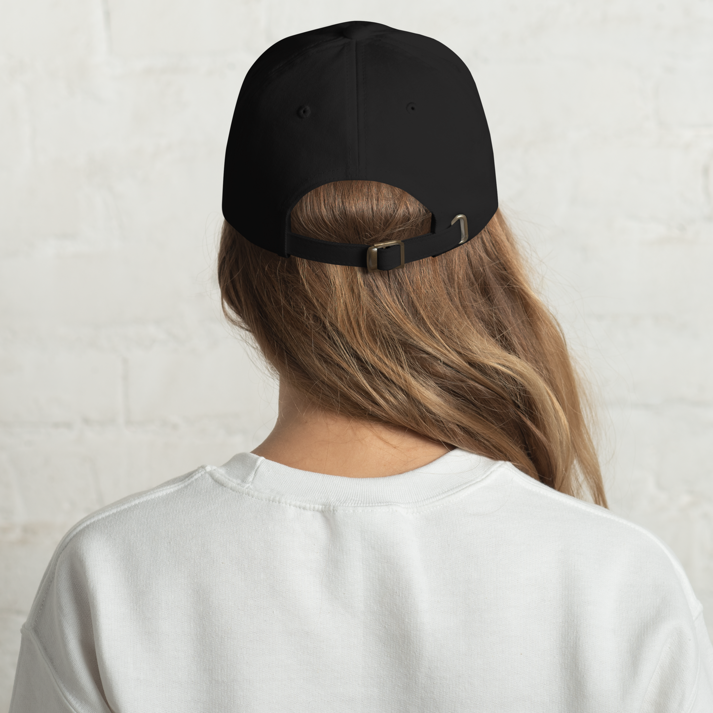 Person wearing a black cap from behind with a plain background