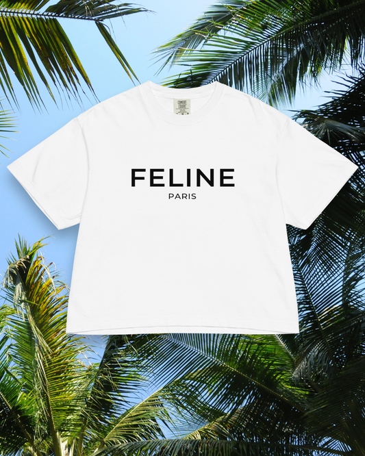 White t-shirt with 'FELINE PARIS' text against a tropical background with palm leaves.