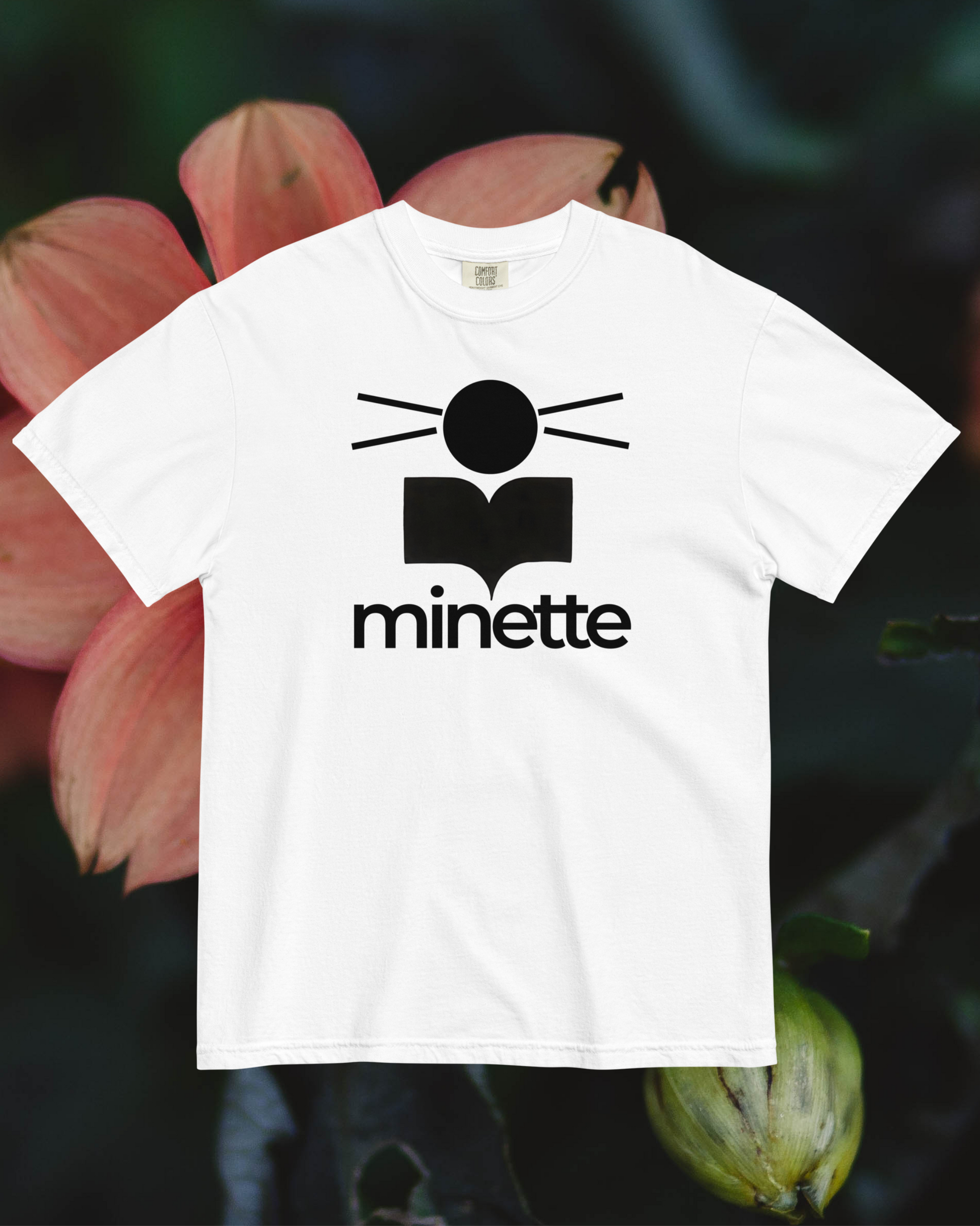 White t-shirt with black logo and text 'minette' against a blurred floral background